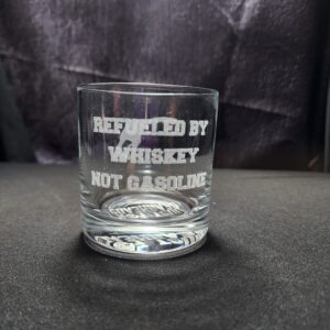 High ball glass engraved with the saying "refueled by whiskey, not gasoline" on one side and a gas nozzle on the opposite side