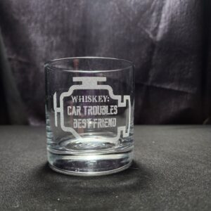 A whiskey glass engraved with the outline of a check engine light and the saying" Whiskey" Car troubles best friend"