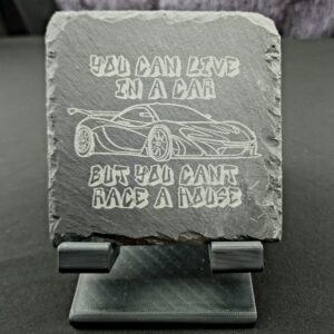 Natural slate coaster engraved with the saying, You can live in a car, but you can't race a house" and the image of a super car outline.